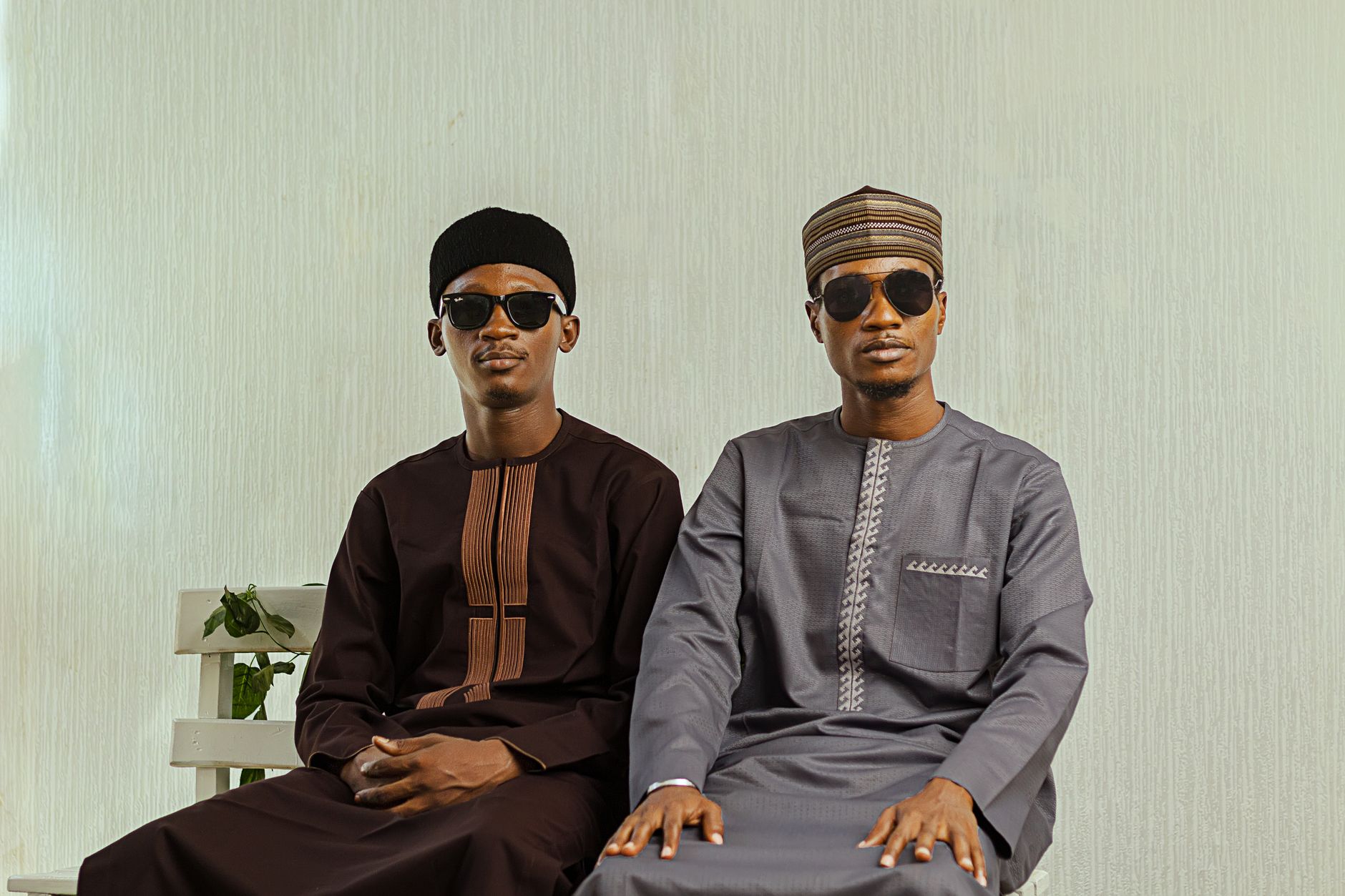 Two men in sunglasses wearing traditional Nigerian attire indoors.