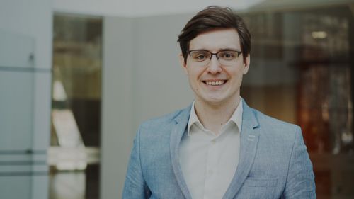 Free Smiling young professional man in a light blue suit indoors, looking confident and approachable. Stock Photo