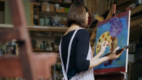 Free A woman artist painting on a canvas in her art studio, creating a colorful piece. Stock Photo