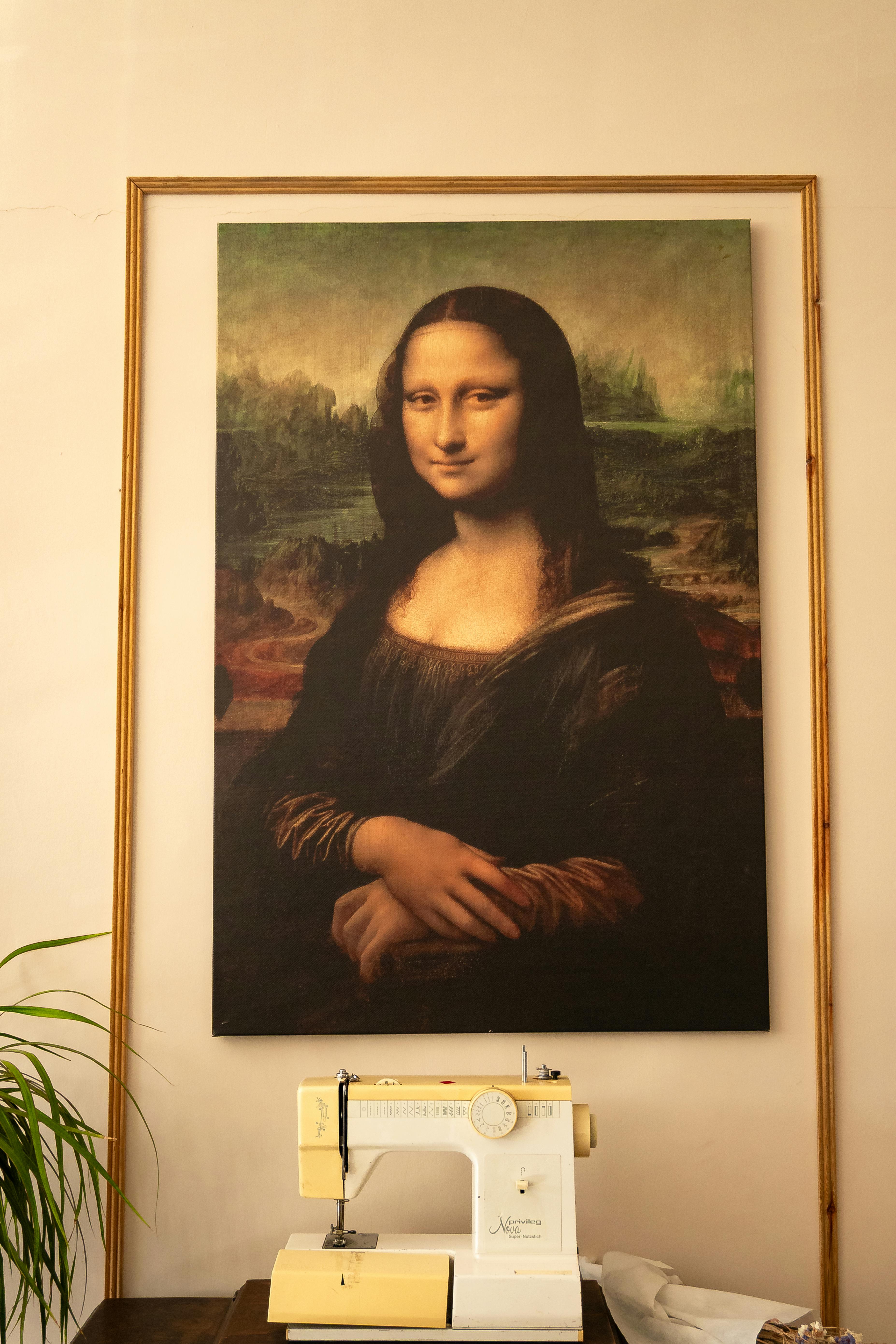 A Mona Lisa poster hangs above a vintage sewing machine in a warmly lit room.