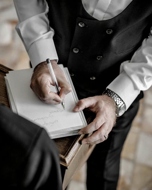 白い本に書いている黒いスーツの男