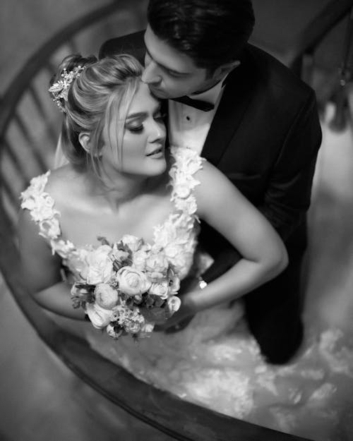 Grayscale Photo of Woman in Wedding Dress Holding Bouquet of Flowers