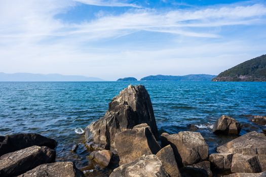 Explore the tranquil beauty of a rocky shoreline with clear blue ocean waves in a serene setting.