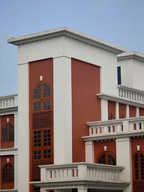 Free Modern building facade with arched windows and contrasting colors against a clear sky. Stock Photo