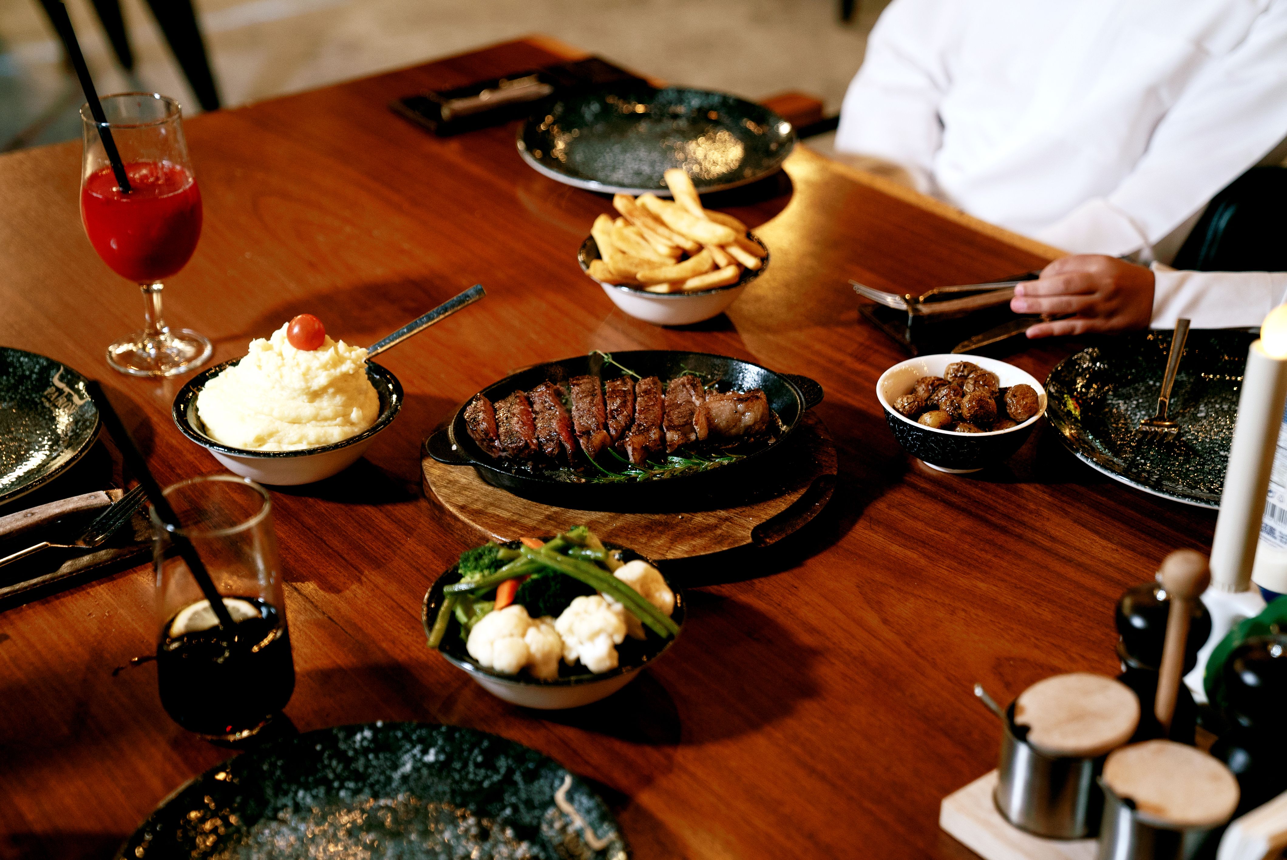 A delicious gourmet meal featuring steak, fries, and vegetables served on a wooden table indoors.