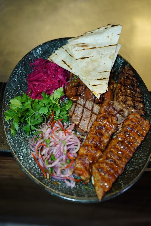 Free A savory Middle Eastern dish featuring grilled meat, fresh herbs, pickled vegetables, and flatbread. Stock Photo