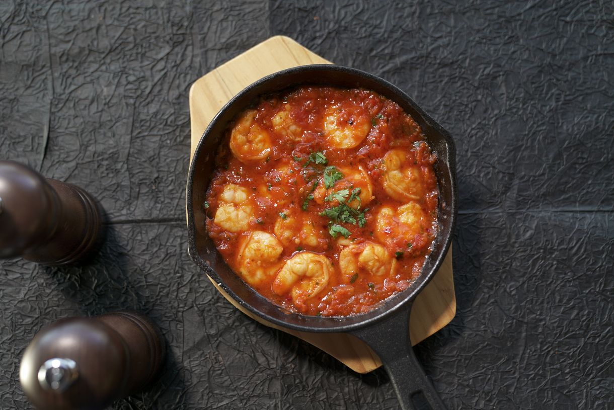 Prawns simmering in a tomato broth in a cast-iron skillet. Photo by Mohamed Olwy on Pexels.