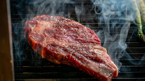 Free Close-up of a juicy steak sizzling on the grill with visible smoke, perfect for barbecue enthusiasts. Stock Photo