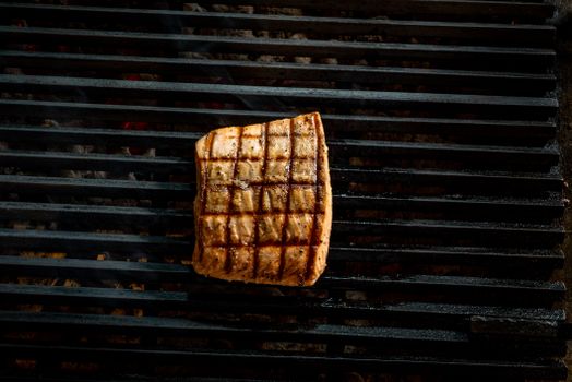 Close-up of a grilled salmon steak with grill marks on a barbecue.