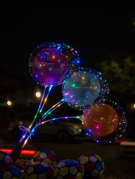 Vibrant LED balloons glowing in the dark night against an urban backdrop.