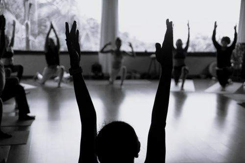 Free A group practicing yoga in a studio with silhouetted figures stretching towards large windows. Stock Photo
