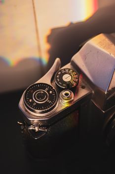 Close-up of a vintage camera in warm light with rainbow reflections.