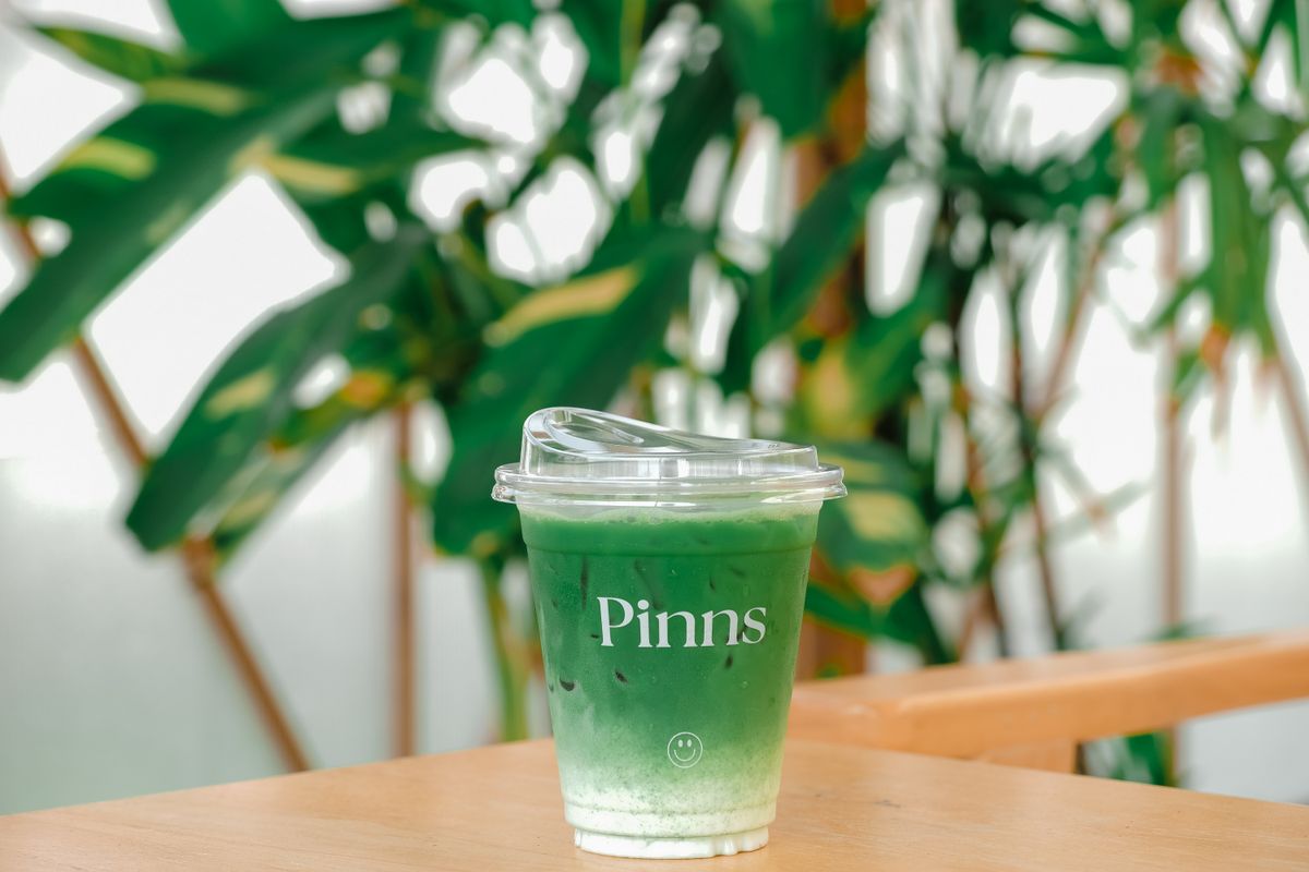 Iced matcha latte on wooden table with green background