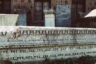 Close-up of an ancient Roman stone inscription with intricate carvings and Latin text.