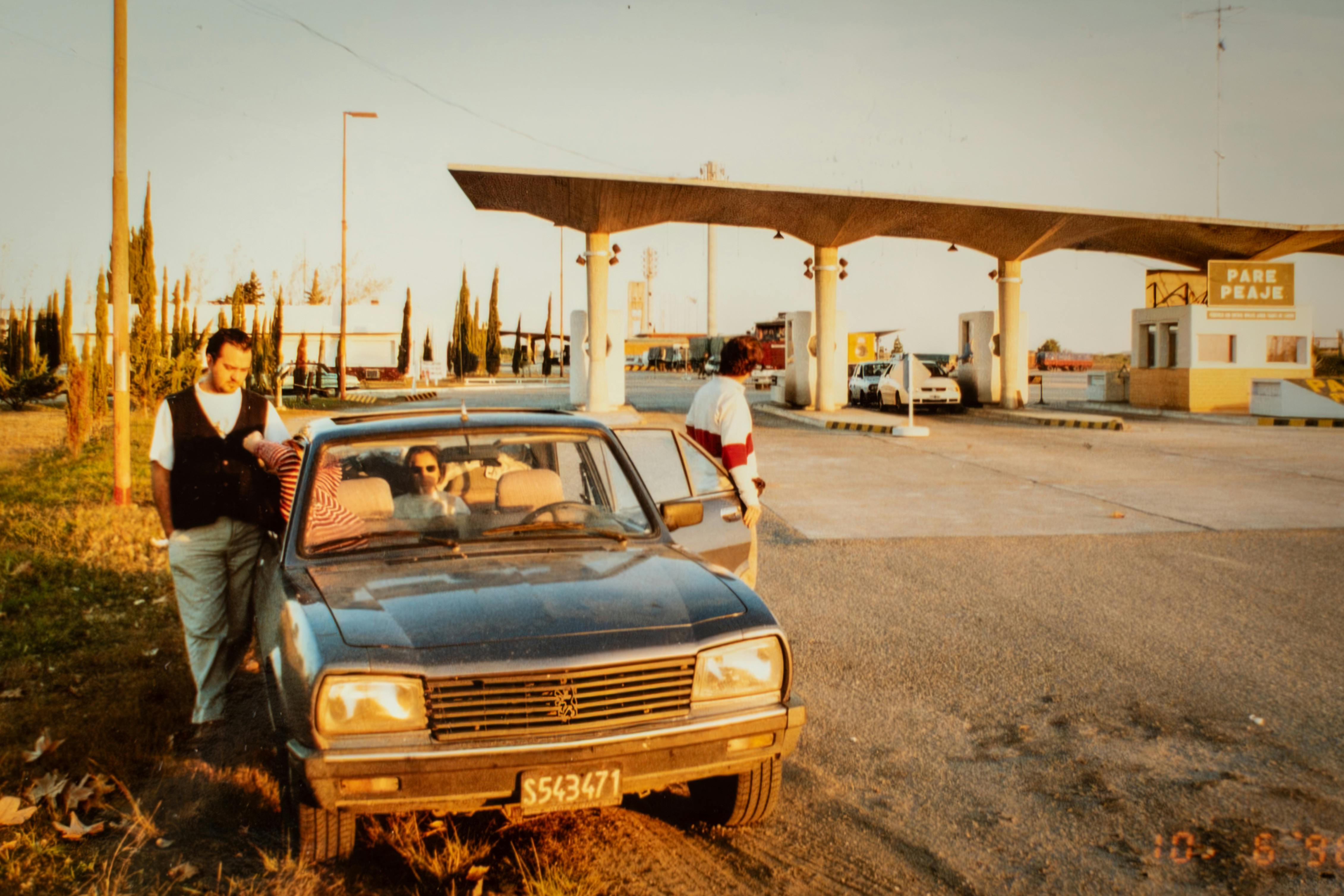 A classic scene of a vintage car at a highway toll booth, capturing a nostalgic moment from the past.