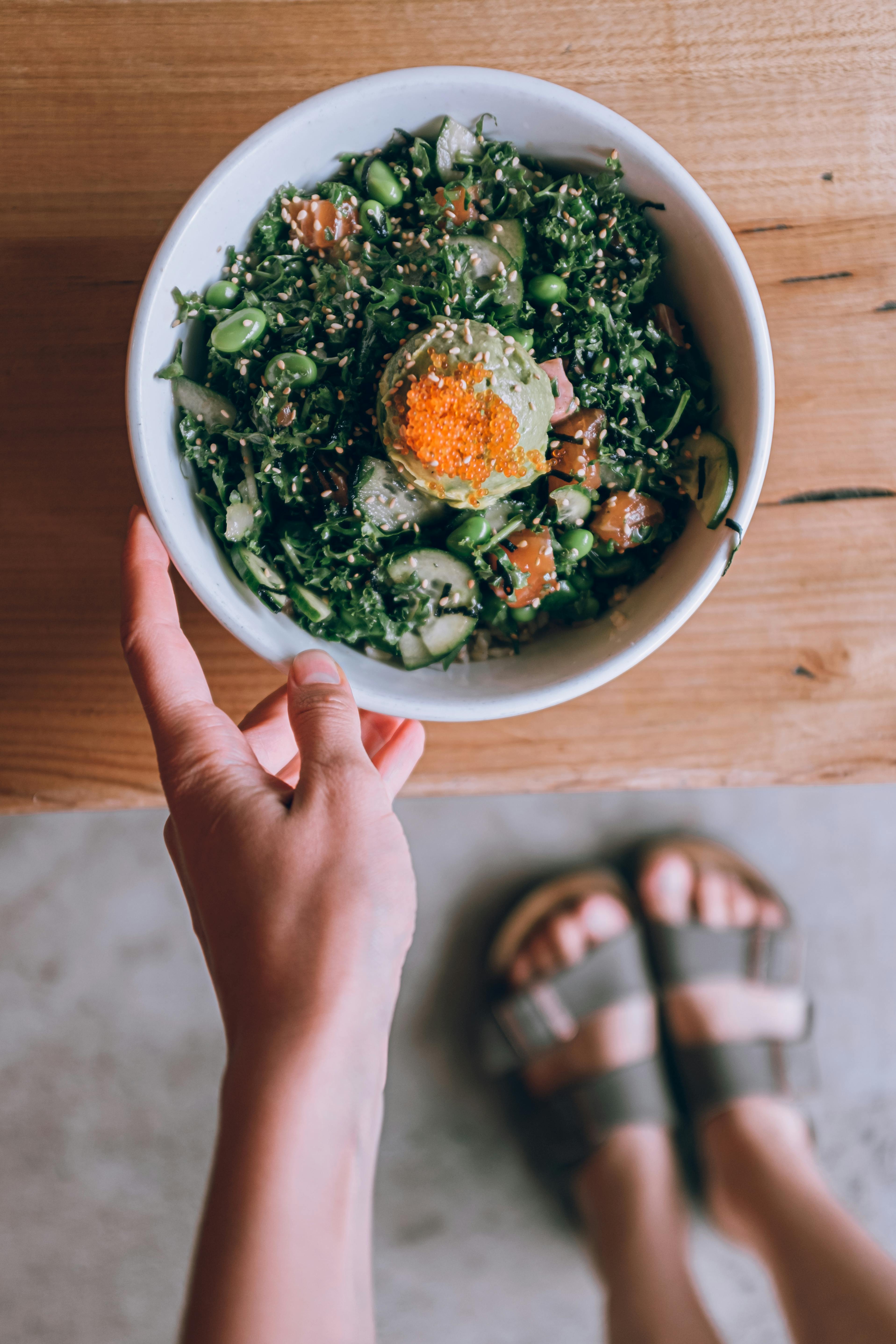 person holding white ceramic bowl with vegetable salad