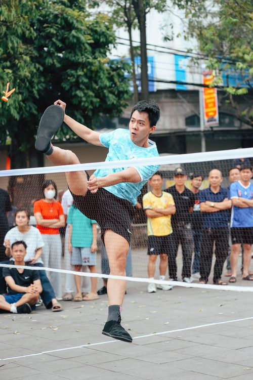Free Man leaps energetically in a vibrant street Sepak Takraw game. Stock Photo