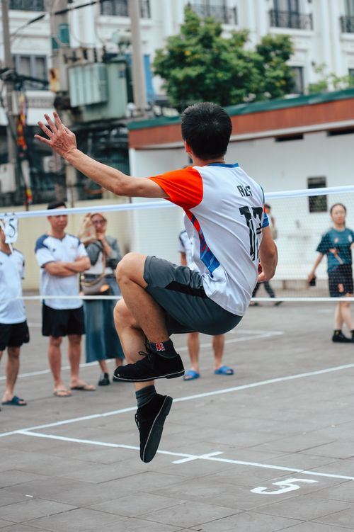 Free Action-packed street volleyball game featuring a player mid-air jump with spectators watching. Stock Photo