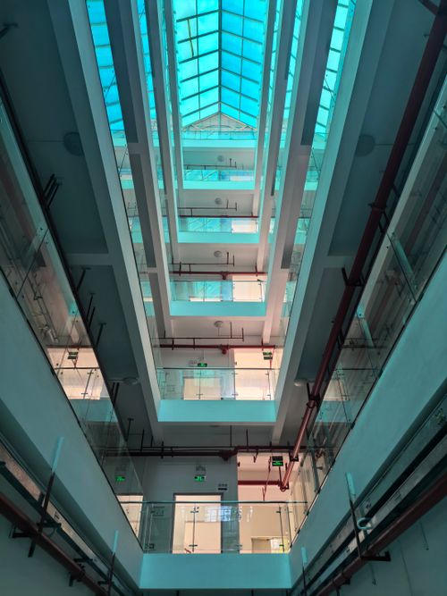 Free View of a multi-level indoor atrium featuring a glass ceiling and minimalist design. Stock Photo