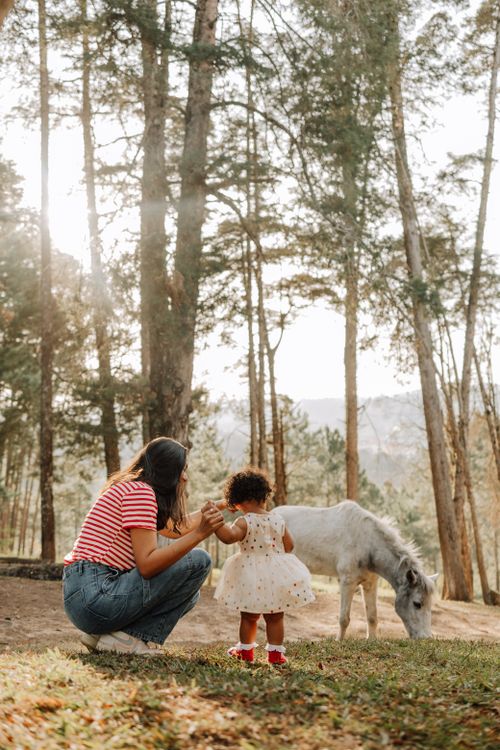 Free A mother and child enjoy a moment with a pony in a tranquil forest setting. Stock Photo