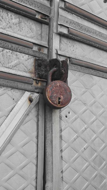 Fotomural Primer plano de un candado oxidado en una puerta de metal texturizada, simbolizando seguridad y decadencia.