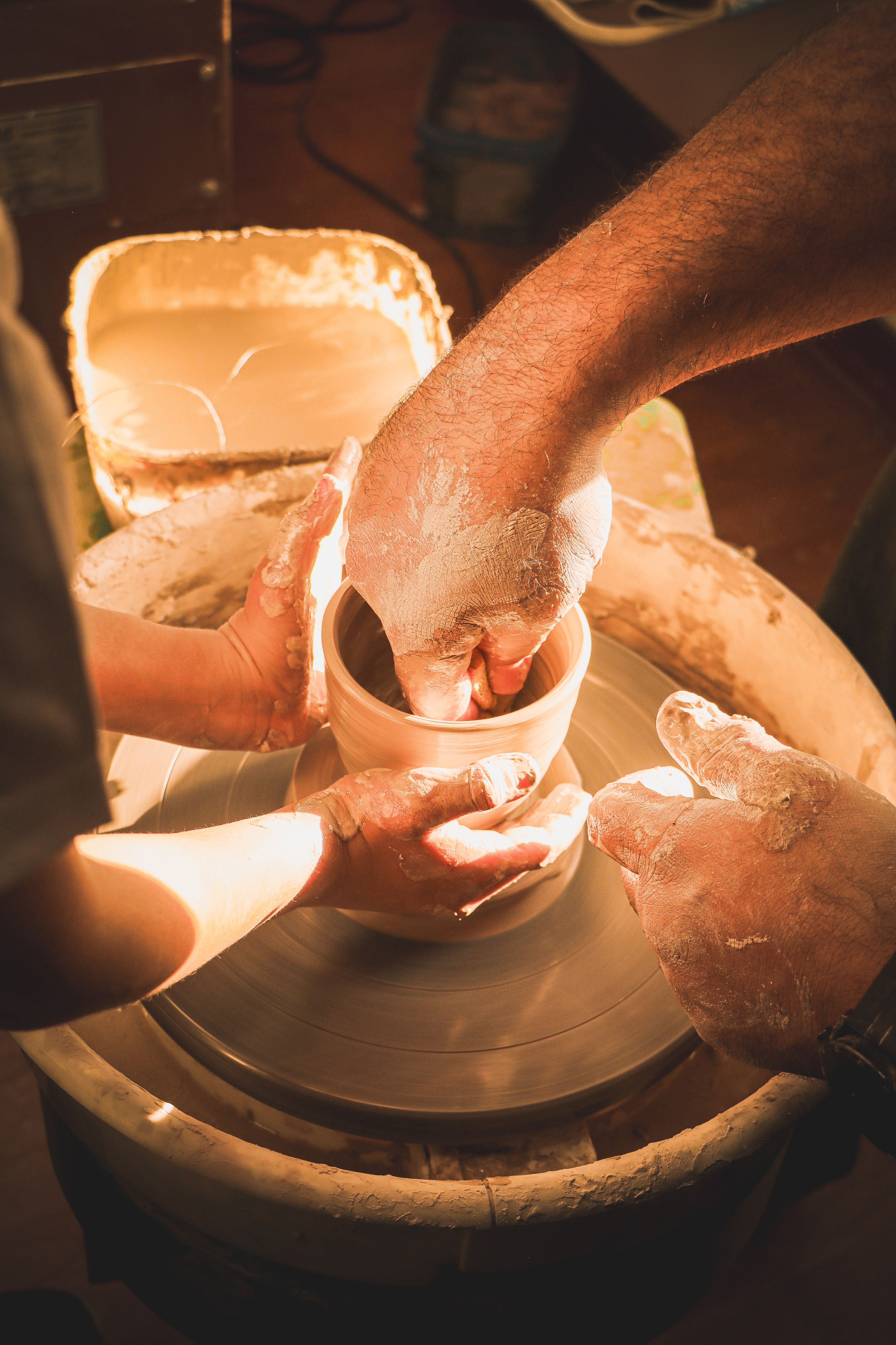 Hands shaping a clay pot on a pottery wheel, showcasing the art of ceramics. Perfect for creative and artistic themes.