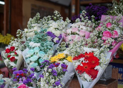 Colorful flower bouquets displayed in a floral shop with roses and daisies.