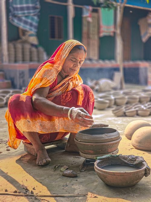 Free A traditional Indian woman shaping clay pots in a rural setting, showcasing artisanal pottery. Stock Photo