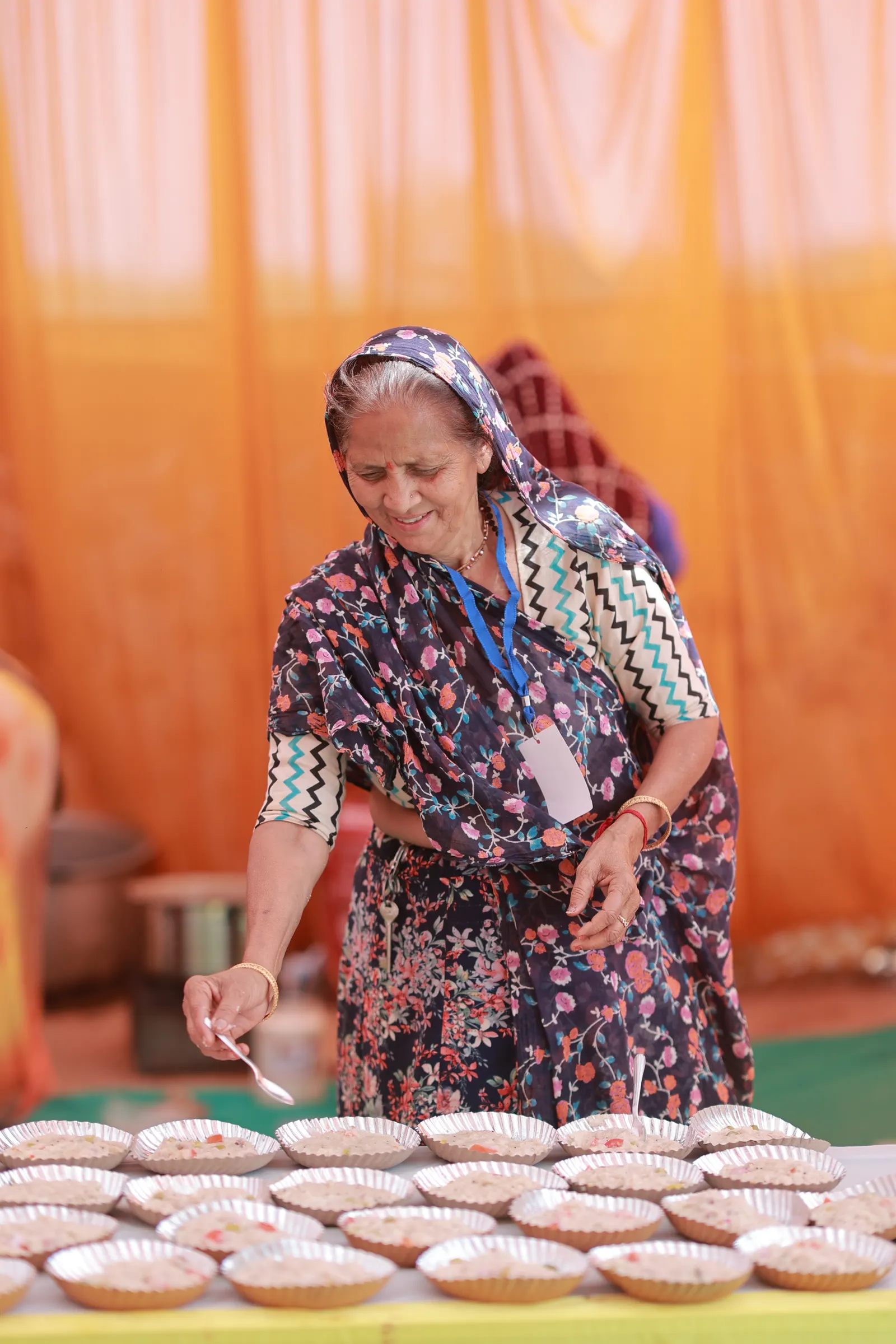 A woman in a saree serving food at a community gathering