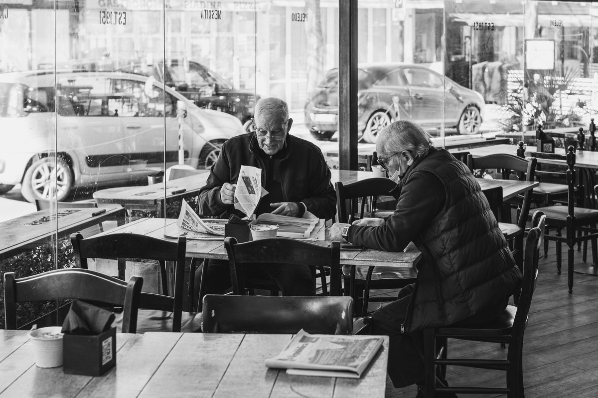 Doi bărbați citesc ziarul la o masă de cafenea