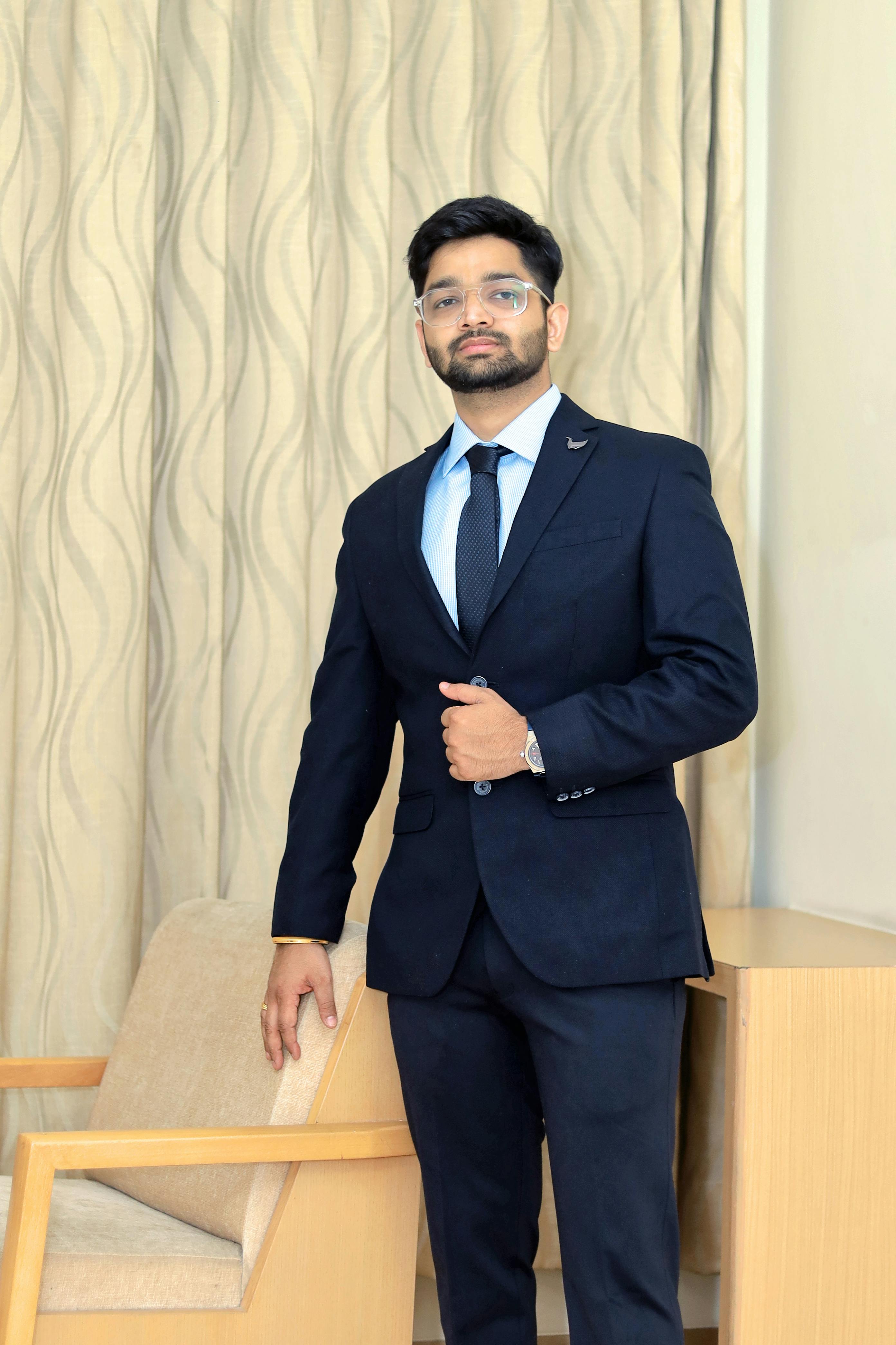 Adult man in formal attire posing indoors; professional fashion photoshoot.