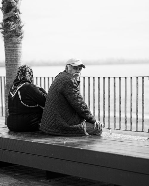 Free Black and white photo of a senior couple seated by the sea, reflecting tranquility. Stock Photo