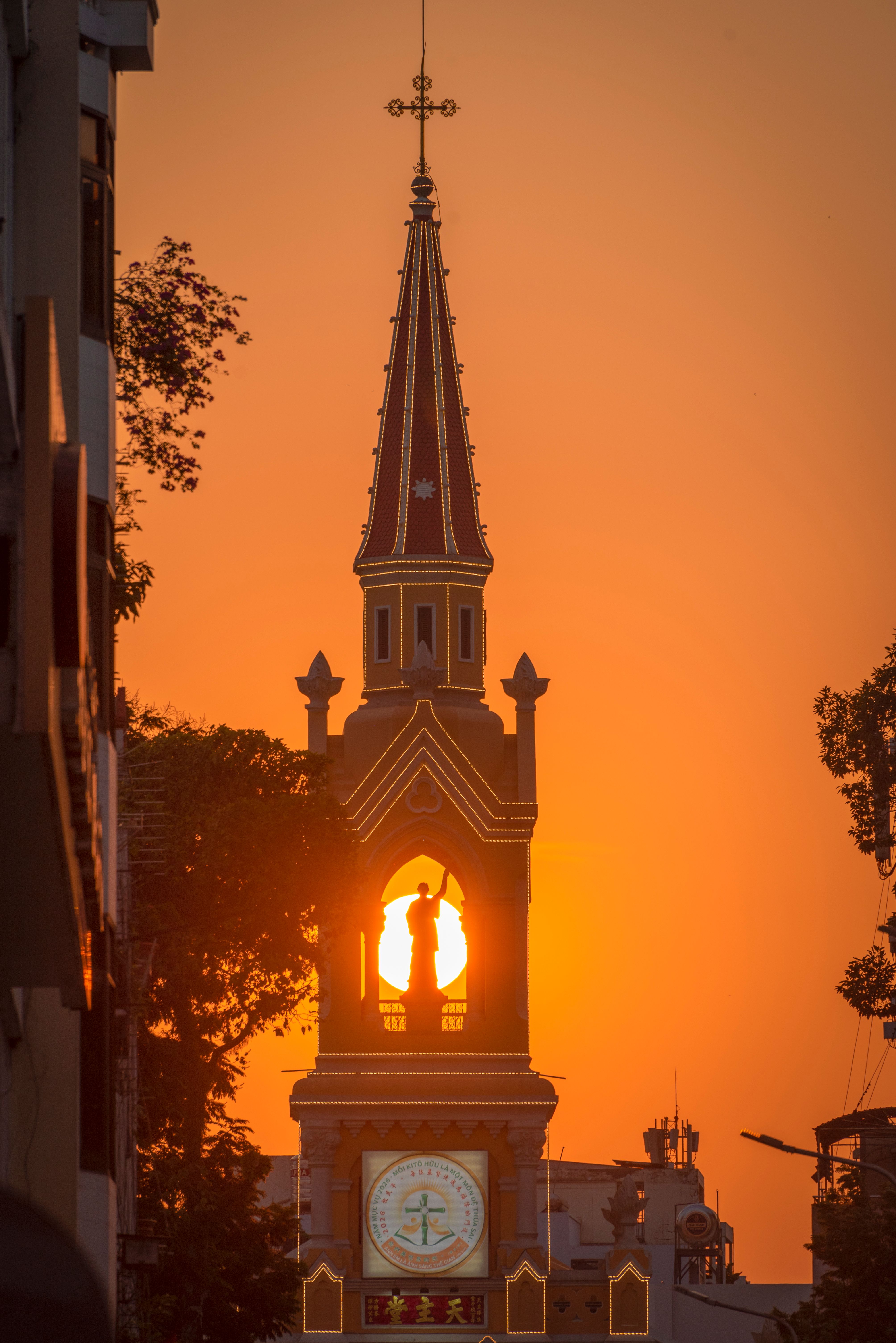 Captivating view of a Saigon church spire silhouetted against a vibrant sunset sky.