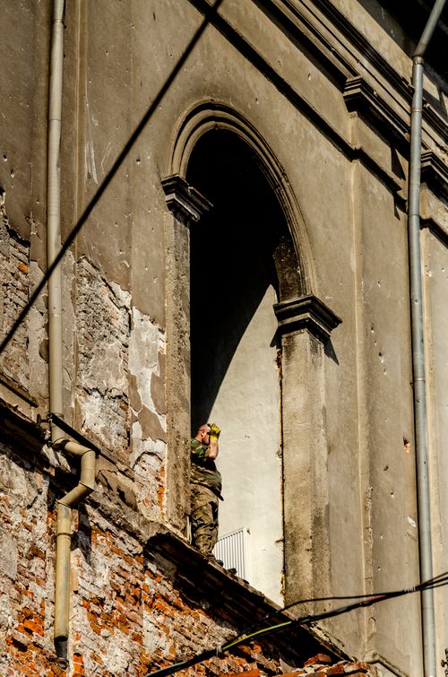 Free A soldier stands watch in an archway of a historic building in Lviv, highlighting the city's architectural charm. Stock Photo