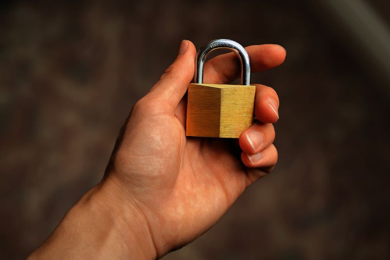 Hand holding a brass padlock, symbolizing security and protection