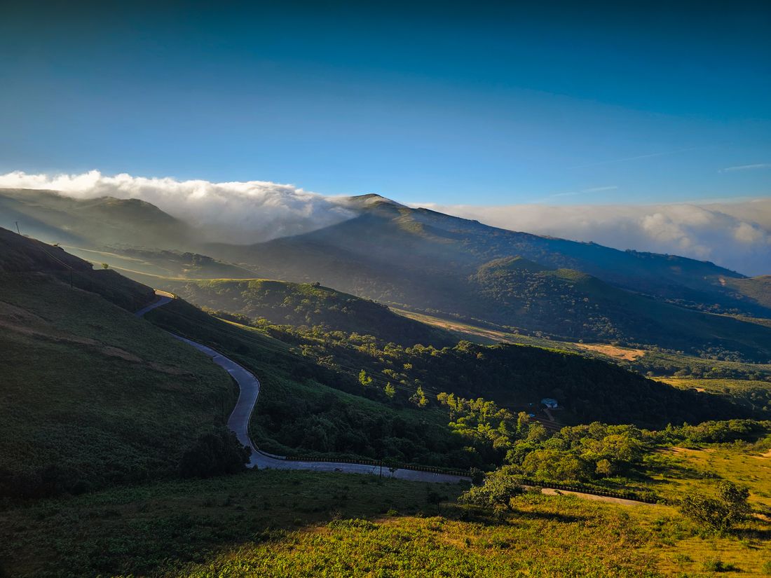 A road winding through green hills at sunrise, photo by Nikhil Shinde on Pexels