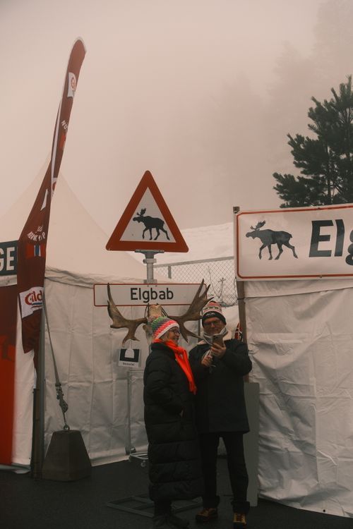 Free Couple at a winter fair with moose-themed signage in a foggy setting. Captured with X-T5 camera. Stock Photo