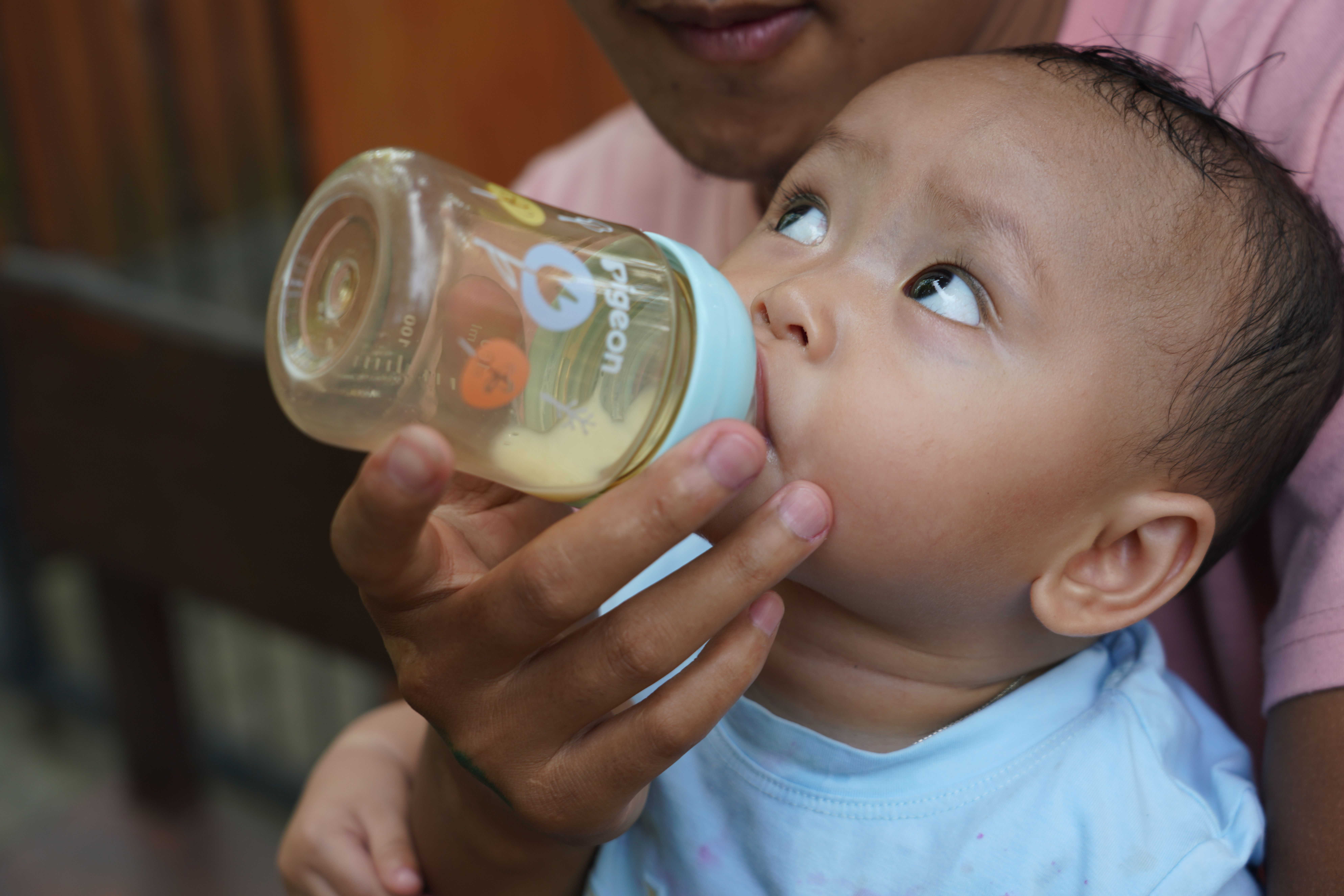 newborn baby holding bottle close-up