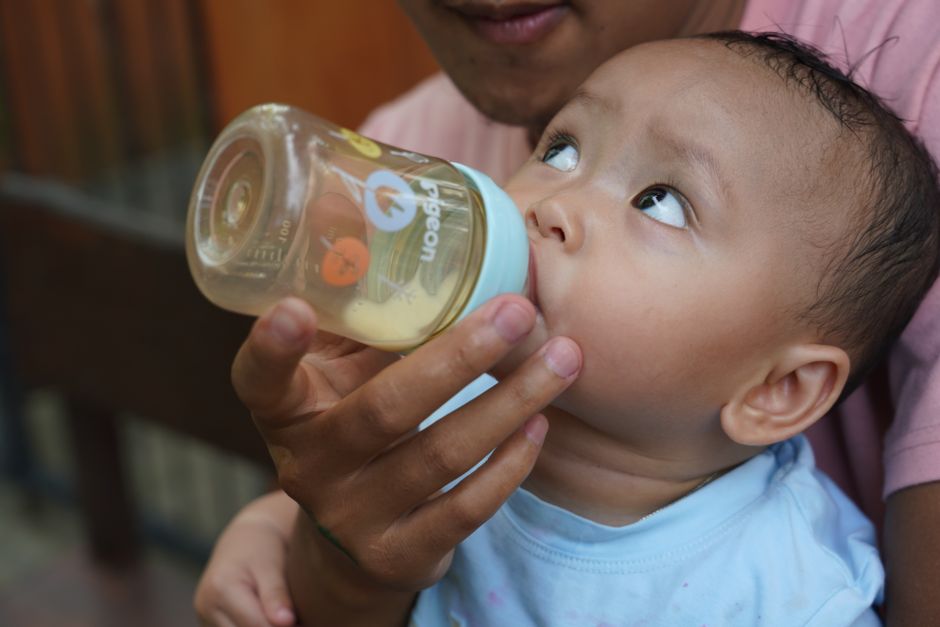 newborn baby holding bottle close-up