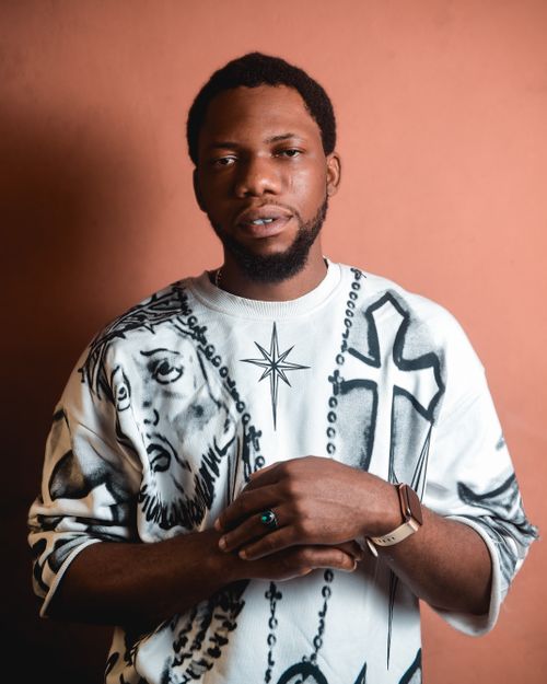 Free A confident man poses in a creative sweatshirt against a warm backdrop. Stock Photo
