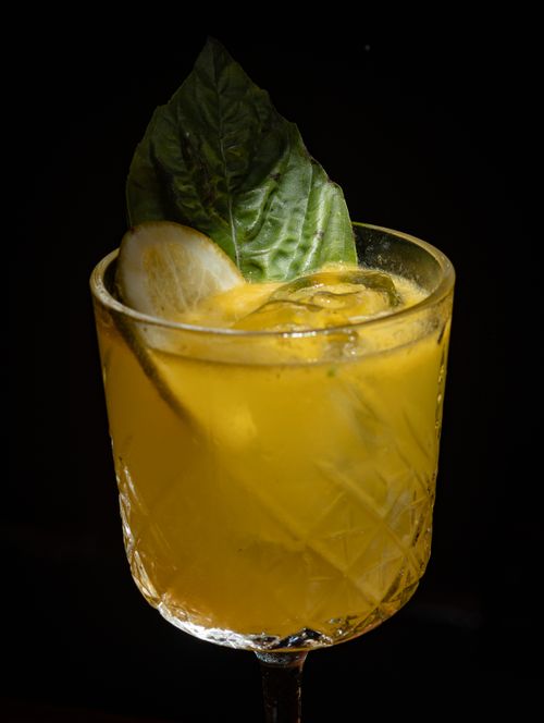 Free Chilled citrus cocktail in a crystal glass with basil garnish, perfect for summer refreshment. Stock Photo