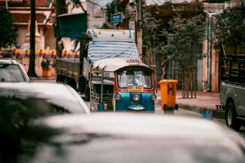 Free Blue Tuk Tuk navigates busy Bangkok street, vibrant urban scene. Stock Photo