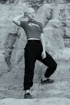 A confident person posing in a stylish outfit against a striking rocky landscape.