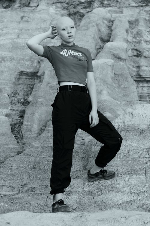 Free A confident person posing in a stylish outfit against a striking rocky landscape. Stock Photo