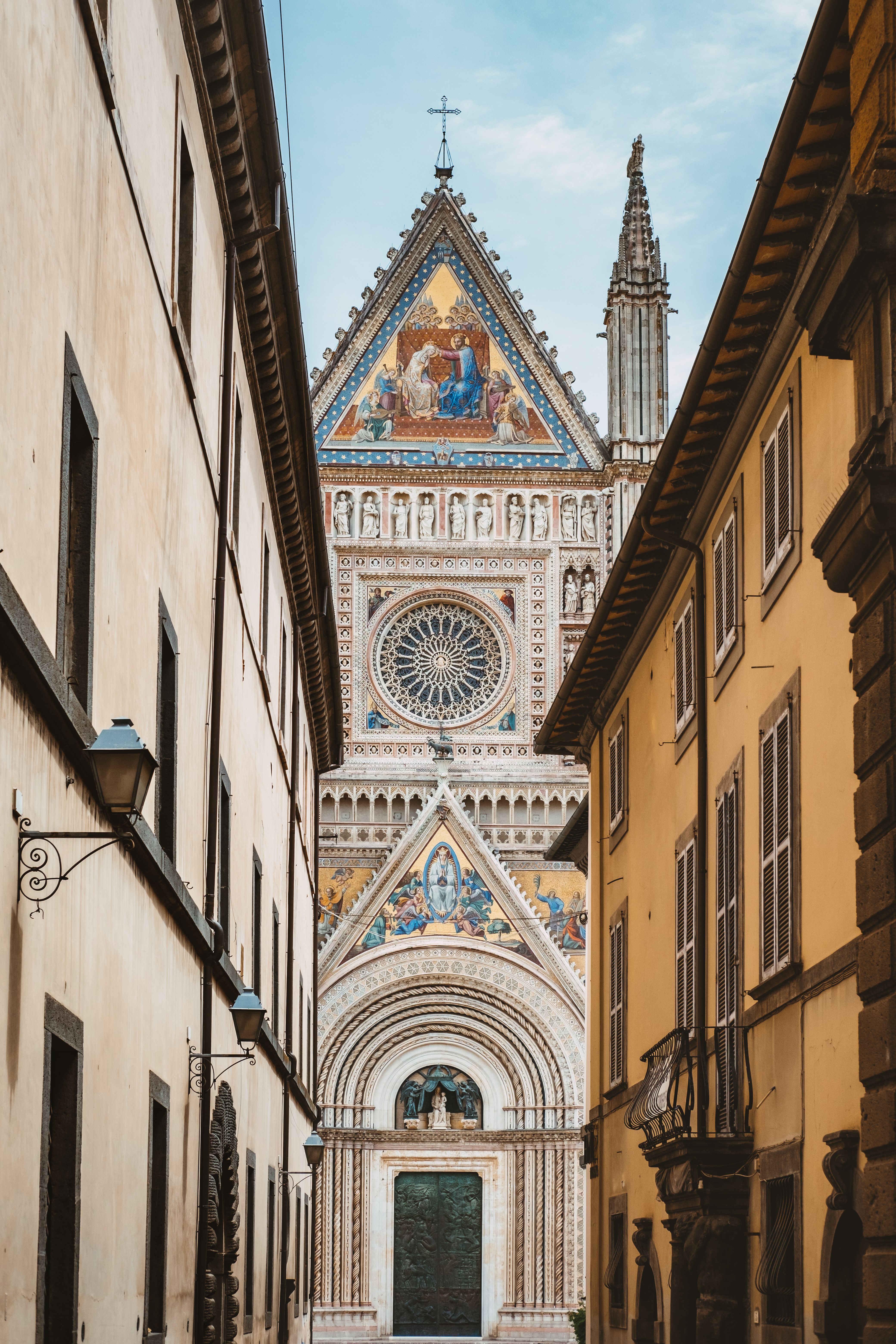 Captivating view of the intricate façade of Orvieto Cathedral in Italy, framed by surrounding buildings on a clear day.