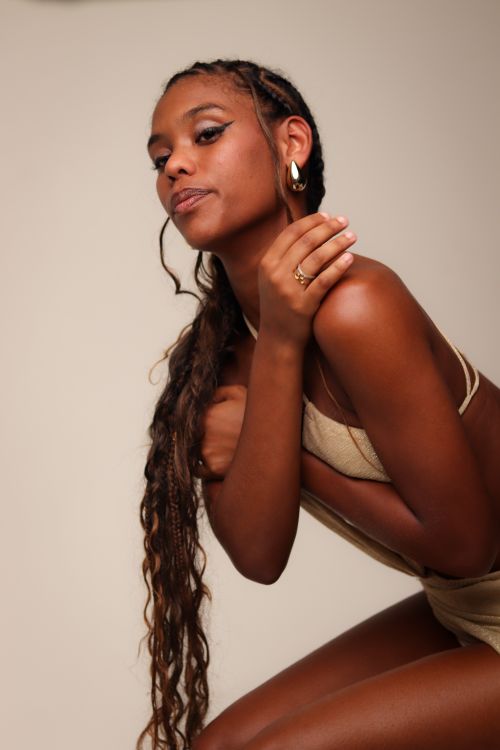 Free Elegant portrait of a young woman with long braids poses confidently against a neutral background. Stock Photo