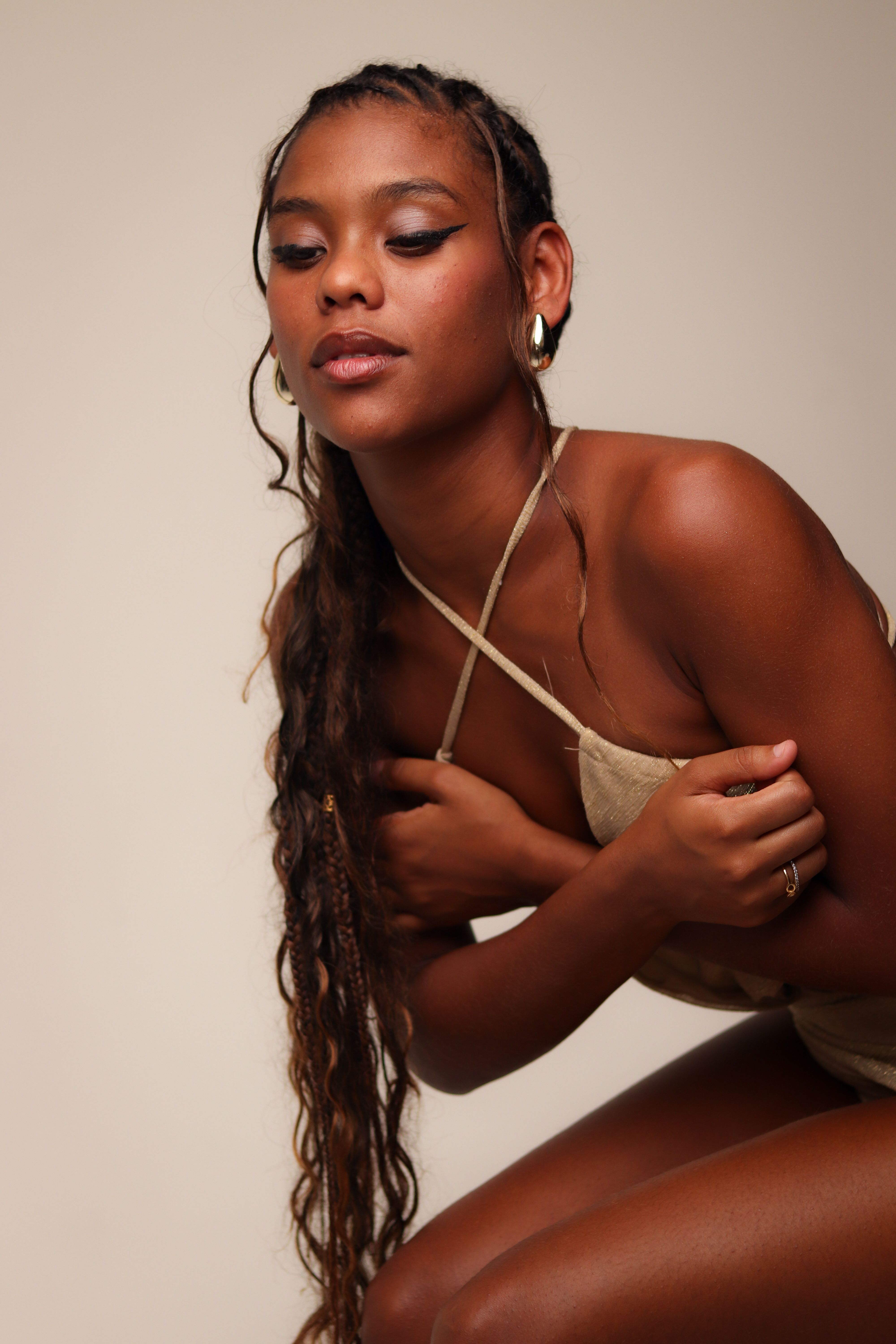 Close-up portrait of a woman with braided hair in a neutral-toned outfit.