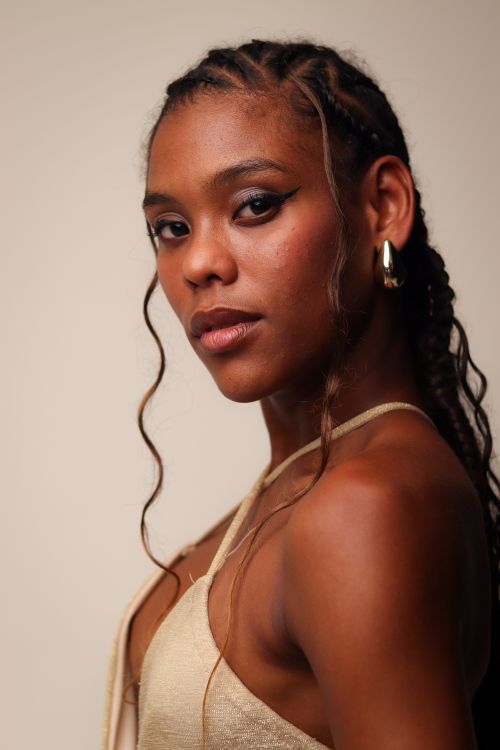 Free Stylish portrait of a woman with cornrow hairstyle and gold earrings against a neutral background. Stock Photo