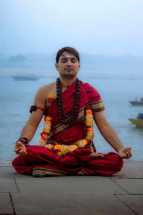 Free A yogi meditates by the river in traditional attire, promoting peace and mindfulness. Stock Photo