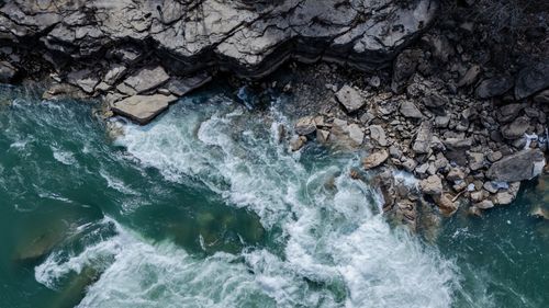 Free A breathtaking aerial shot of a river flowing alongside a rocky shoreline. Stock Photo